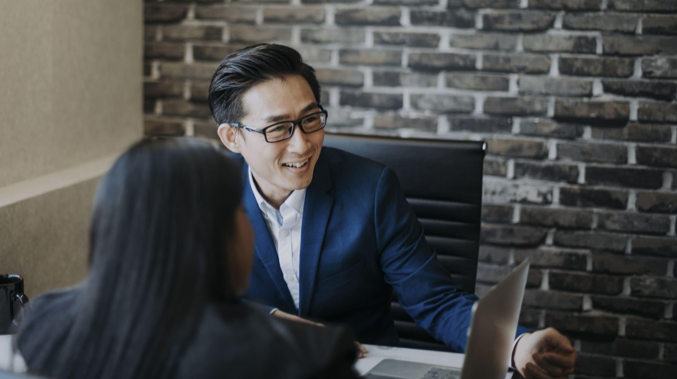 2 asian chinese white collar workers having discussion  using laptop